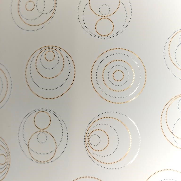 Cadeaupapier spiegel glanzende stippen in cirkelvorm met een mat crème achtergrond.
 